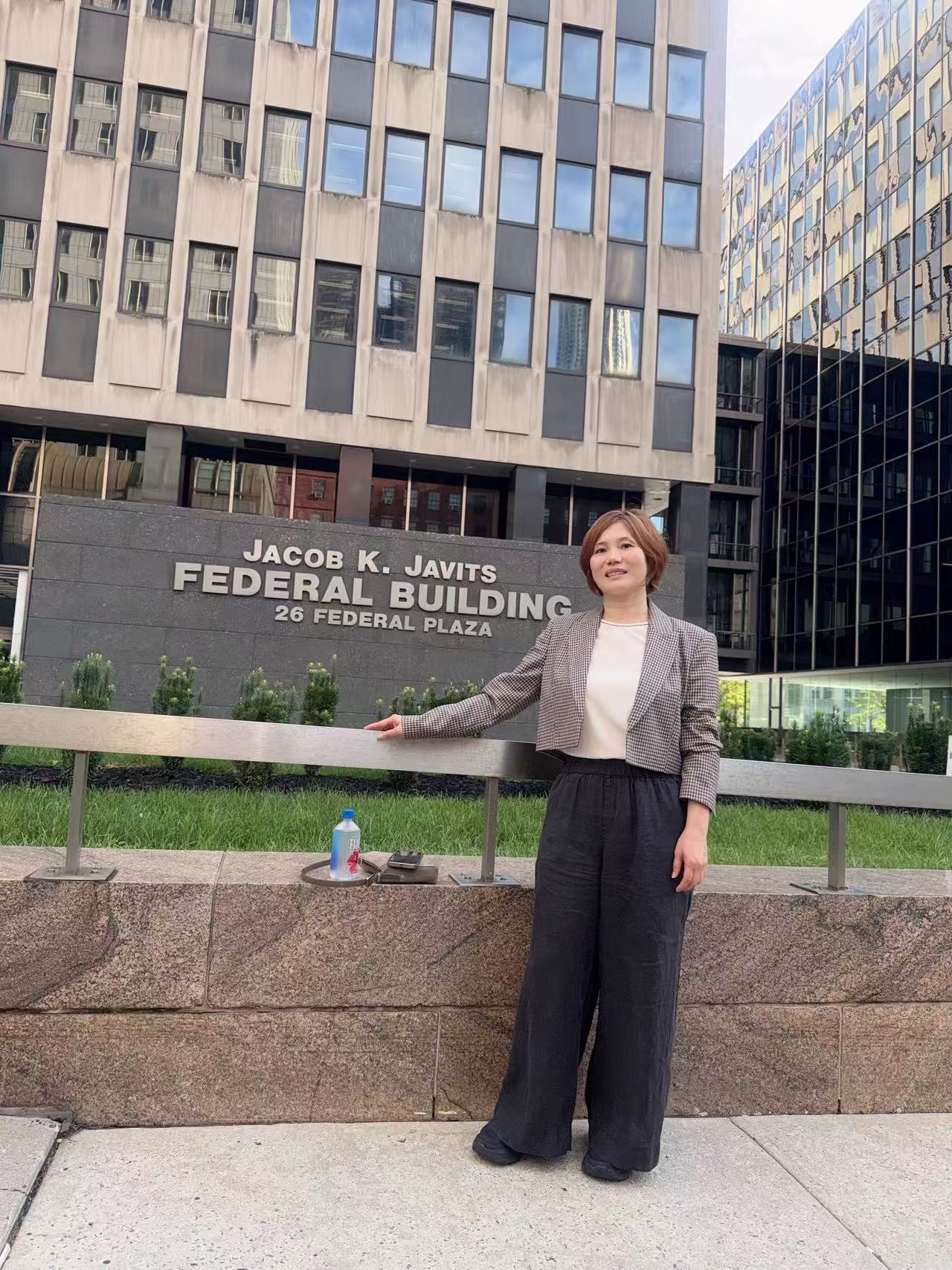 协会成员在 26 Federal Plaza 联邦大楼标识前留影